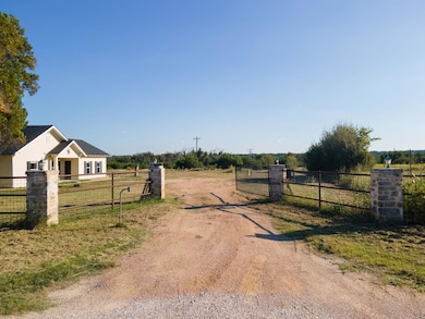 View of dirt / gravel road with a view of countryside, a gate, and a gated entry