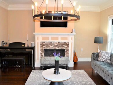 Living room featuring crown molding, baseboards, a chandelier, and wood-type flooring