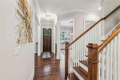 Foyer entrance featuring dark wood-style floors, stairs, ornamental molding, and a chandelier