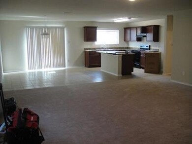 Kitchen with dark brown cabinetry, electric stove, light tile floors, and a kitchen island