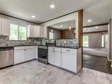Kitchen with white cabinetry, appliances with stai