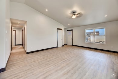Empty room featuring vaulted ceiling, light wood-type flooring, recessed lighting, and a ceiling fan