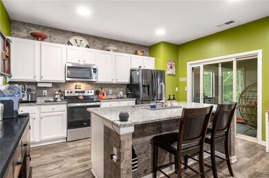 Kitchen featuring stainless steel appliances, light wood-type flooring, a sink, white cabinetry, and recessed lighting