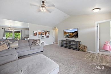 Carpeted living area featuring ceiling fan, vaulted ceiling, and arched walkways