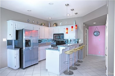 Kitchen with a peninsula, white cabinetry, appliances with stainless steel finishes, and backsplash