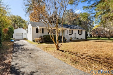Single story home featuring an outbuilding, asphalt driveway, a detached garage, and a front lawn