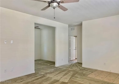 Carpeted empty room with a ceiling fan and baseboa