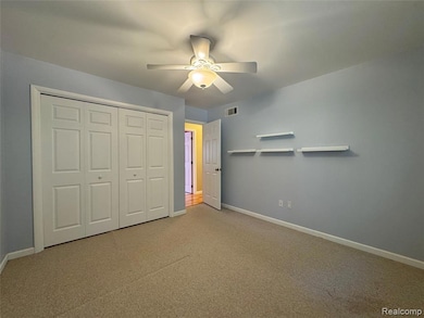 Unfurnished bedroom featuring carpet floors, a closet, and a ceiling fan