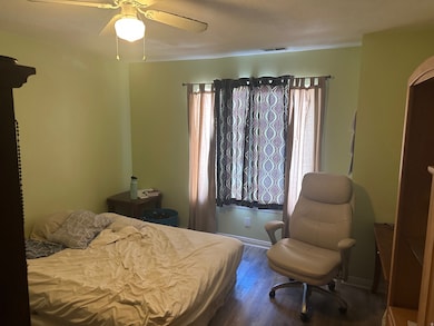 Bedroom with wood finished floors, multiple windows, and ceiling fan