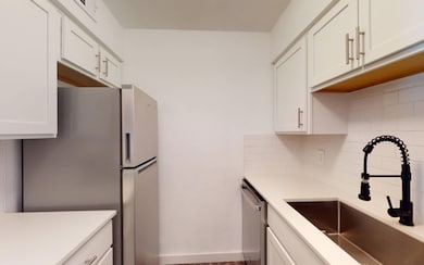 Kitchen featuring backsplash, sink, white cabinets