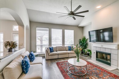 Living room with a fireplace, vaulted ceiling, light hardwood / wood-style flooring, and ceiling fan