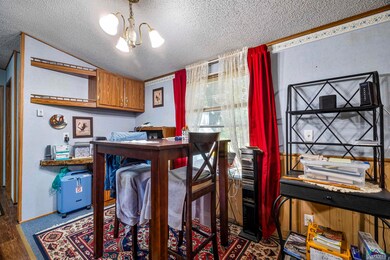 Carpeted dining area with an office area, a textured ceiling, and a chandelier