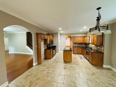 Kitchen featuring appliances with stainless steel finishes, arched walkways, brown cabinets, crown molding, and recessed lighting