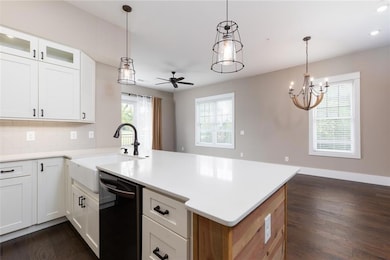 Kitchen featuring white cabinets, dark wood-type flooring, decorative light fixtures, and a peninsula