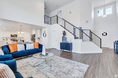 Living room featuring a towering ceiling, wood finished floors, stairs, and a chandelier