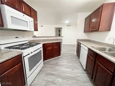 Kitchen with white appliances, light countertops, and a peninsula
