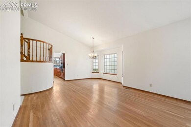 Spare room featuring a chandelier, light wood-style floors, lofted ceiling, and stairway