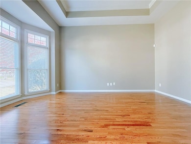 Empty room featuring light wood-style flooring, a tray ceiling, and crown molding