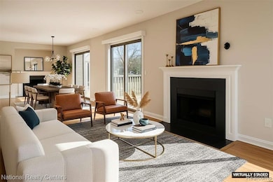 Living room featuring a fireplace with flush hearth, light wood-style flooring, and a chandelier