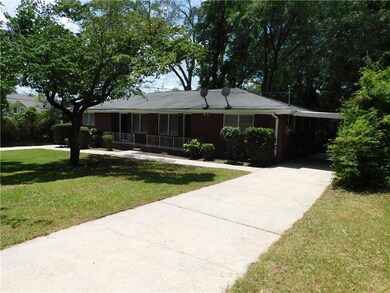 View of front facade with driveway, a front yard, covered porch, and an attached carport