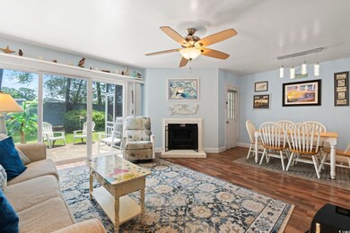 Living area with track lighting, wood finished floors, a fireplace with raised hearth, and ceiling fan
