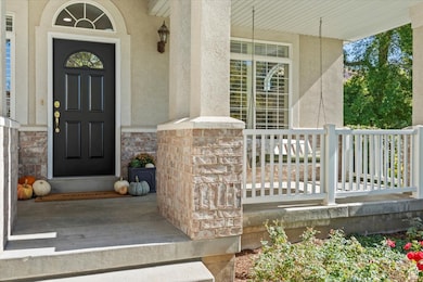 View of exterior entry featuring stone siding, stucco siding, and a porch