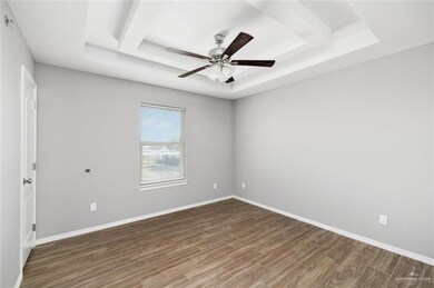 Empty room featuring a raised ceiling, wood finished floors, and a ceiling fan