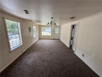 Empty room with a chandelier, dark colored carpet, ornamental molding, and electric panel