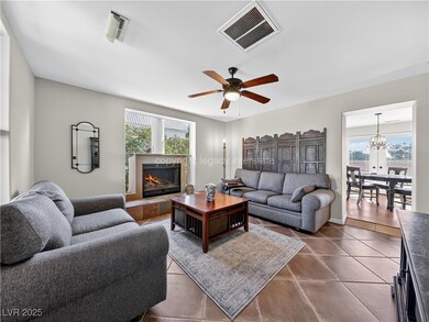 Living room with ceiling fan, healthy amount of natural light, dark tile patterned flooring, and a chandelier