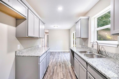 Kitchen featuring gray cabinets, light wood-style flooring, and light stone counters