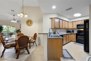 Kitchen with black appliances, a chandelier, light tile patterned flooring, ceiling fan, and stone countertops