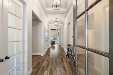 Wide entrance, high, tray ceilings with modern fixtures. The home office is on the left, behind the French doors.