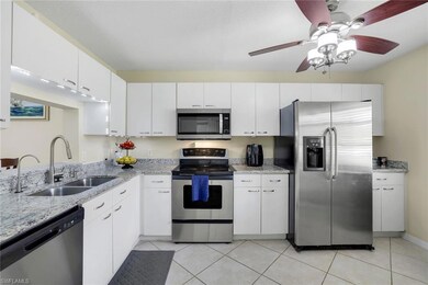 Kitchen with stainless steel appliances, white cabinets, and light stone countertops