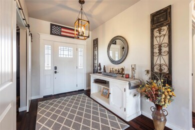Foyer with dark wood-style floors, a chandelier, and a barn door