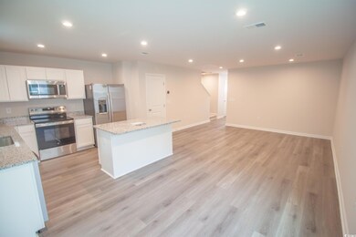 Kitchen featuring appliances with stainless steel finishes, a center island, recessed lighting, white cabinetry, and light wood-type flooring