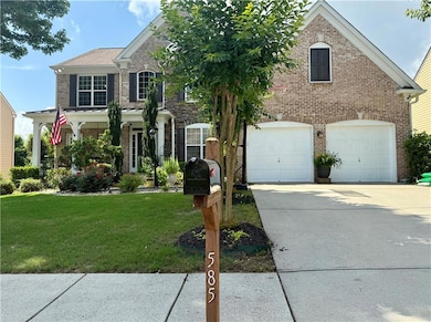 Traditional-style home with brick siding, a garage, a front yard, and driveway