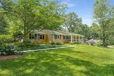 Ranch-style home with a front lawn, covered porch, and brick siding