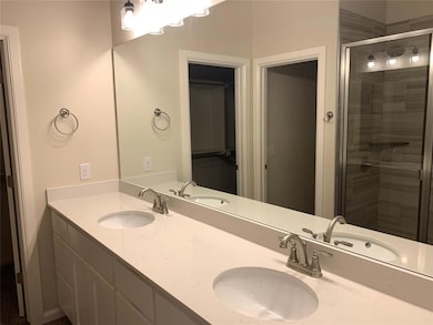 Bathroom featuring a stall shower, double vanity, and a walk in closet