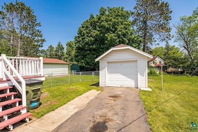 Detached garage with driveway and view of wooded area