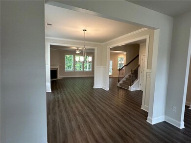 Unfurnished living room with a chandelier, dark wood finished floors, stairway, ornamental molding, and baseboards
