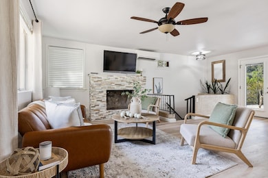 Living room with a wall unit AC, ceiling fan, woo