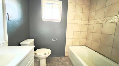 Bathroom featuring vanity, a washtub, and toilet