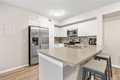 Kitchen with appliances with stainless steel finishes, a sink, baseboards, a peninsula, and tasteful backsplash