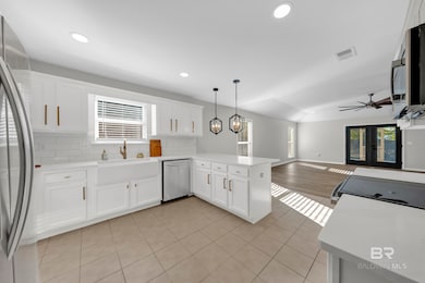 Kitchen with white cabinetry, backsplash, stainless steel appliances, recessed lighting, and hanging light fixtures