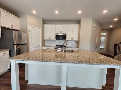 Kitchen featuring stainless steel appliances, a sink, a kitchen island with sink, tasteful backsplash, and white cabinets