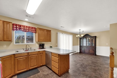 Kitchen featuring brown cabinetry, healthy amount of natural light, a peninsula, light countertops, and a textured ceiling