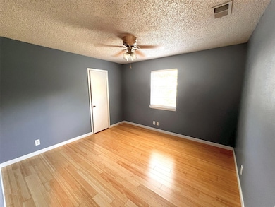 Empty room featuring a textured ceiling, light wood finished floors, and a ceiling fan