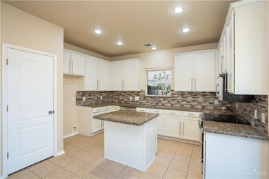 Kitchen featuring a kitchen island, dark stone countertops, white cabinetry, and electric stove