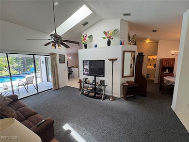 Carpeted living room with a ceiling fan, a chandel