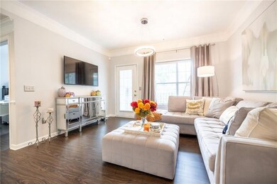 Living area featuring dark wood finished floors, crown molding, and baseboards